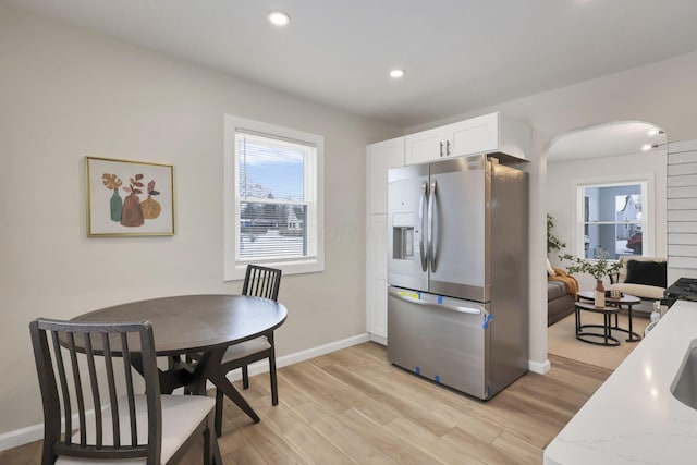 kitchen featuring light hardwood / wood-style flooring, white cabinets, stainless steel fridge, and light stone counters