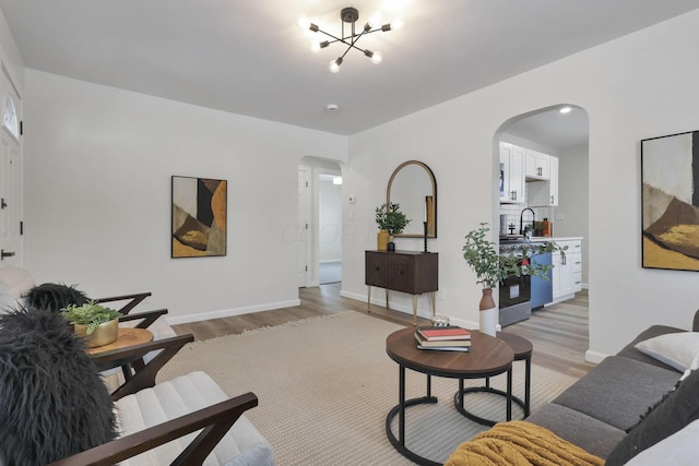 living room featuring an inviting chandelier, light hardwood / wood-style flooring, and sink