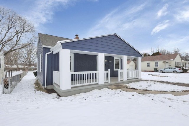 snow covered back of property featuring a porch