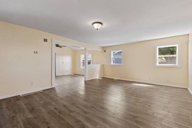 empty room with ceiling fan, plenty of natural light, and dark hardwood / wood-style floors