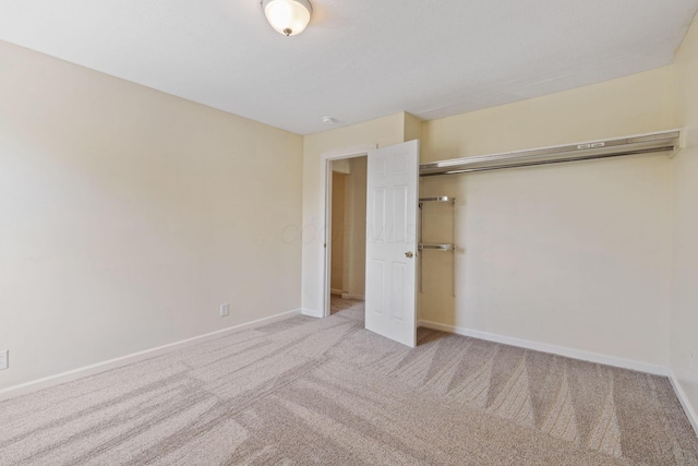 unfurnished bedroom with a closet and light colored carpet