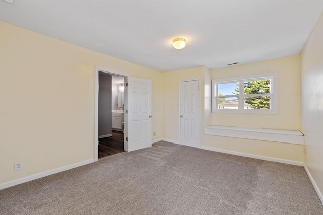 unfurnished bedroom featuring ensuite bathroom, carpet flooring, and a closet