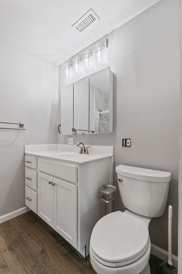 bathroom with toilet, vanity, and hardwood / wood-style flooring