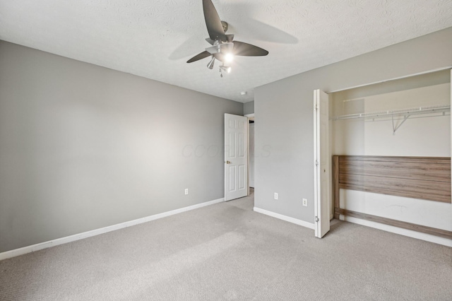 unfurnished bedroom with a textured ceiling, carpet floors, a ceiling fan, baseboards, and a closet