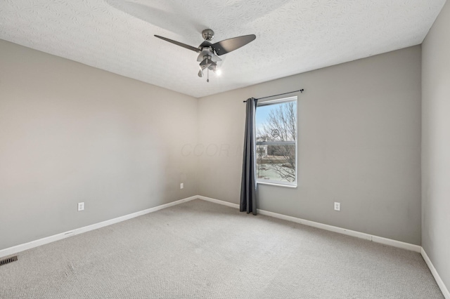 empty room with a ceiling fan, carpet floors, baseboards, and a textured ceiling