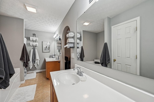 bathroom featuring a textured ceiling, two vanities, a sink, baseboards, and tile patterned floors