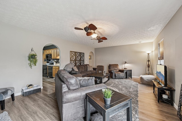 living area featuring arched walkways, baseboards, and wood finished floors