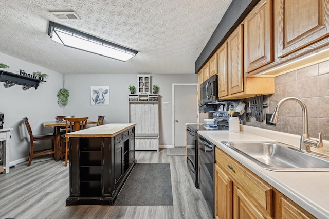 kitchen with light wood-style flooring, a sink, visible vents, tasteful backsplash, and stainless steel microwave