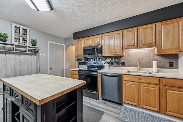 kitchen with arched walkways, stainless steel appliances, tasteful backsplash, light wood-style flooring, and a sink