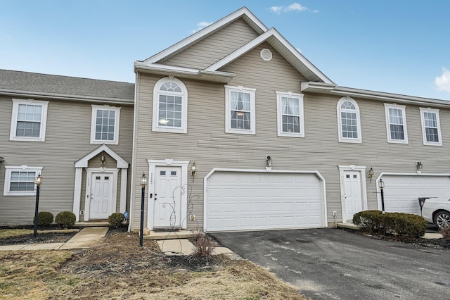 townhome / multi-family property featuring aphalt driveway and an attached garage