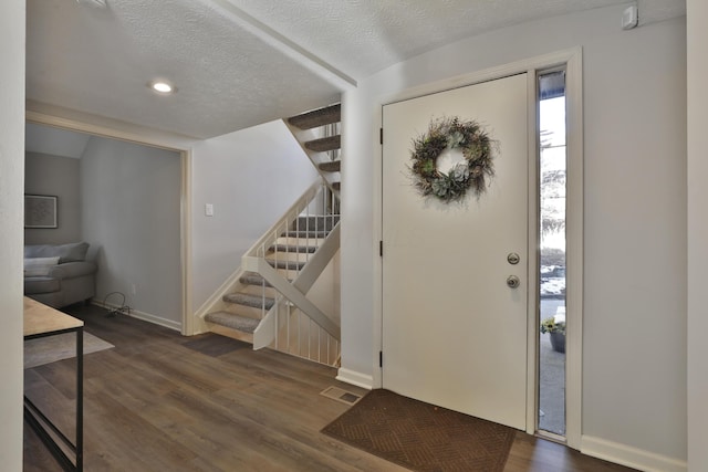 entryway featuring dark wood-type flooring and a textured ceiling