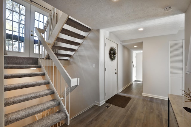 stairway with wood-type flooring and a textured ceiling