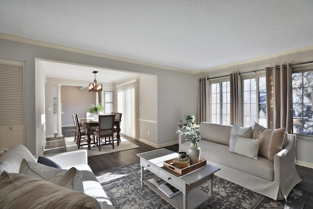 living room featuring crown molding, a healthy amount of sunlight, dark hardwood / wood-style floors, and decorative columns