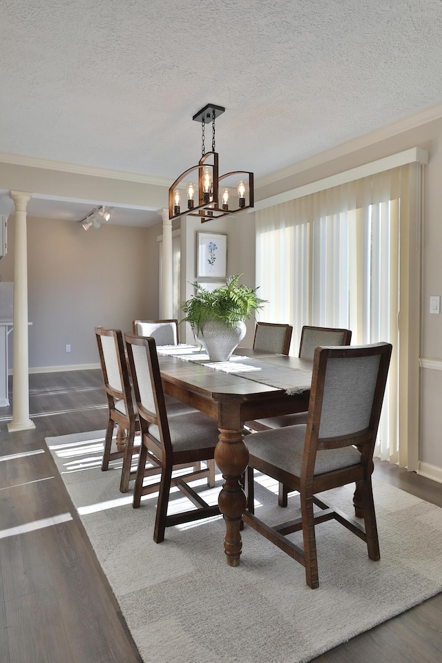 dining area with crown molding, decorative columns, dark hardwood / wood-style floors, and a textured ceiling