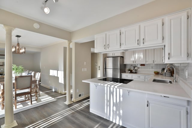 kitchen featuring stainless steel refrigerator, white cabinetry, sink, and ornate columns