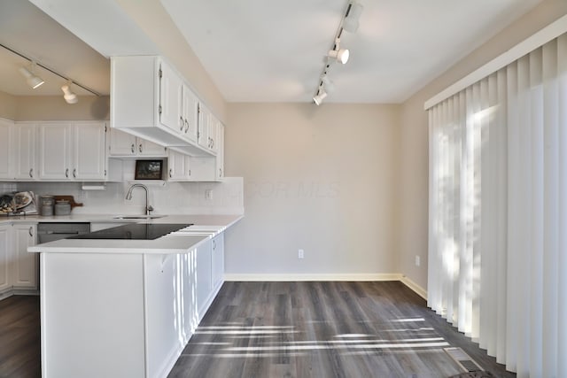 kitchen with sink, white cabinetry, tasteful backsplash, dark hardwood / wood-style floors, and kitchen peninsula