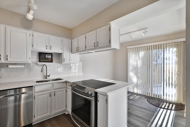 kitchen featuring sink, dark wood-type flooring, appliances with stainless steel finishes, white cabinetry, and decorative backsplash