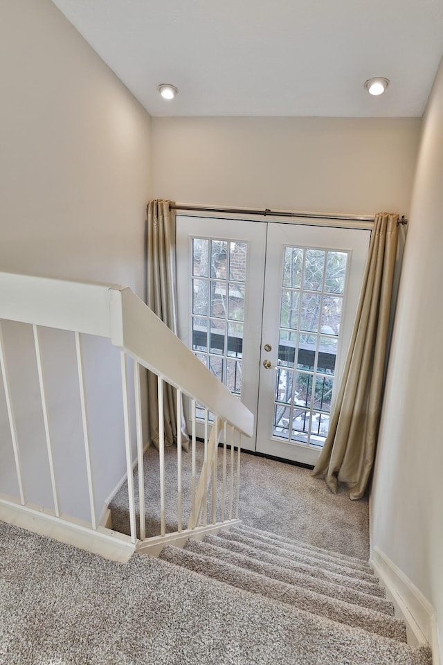 stairs with carpet floors and french doors