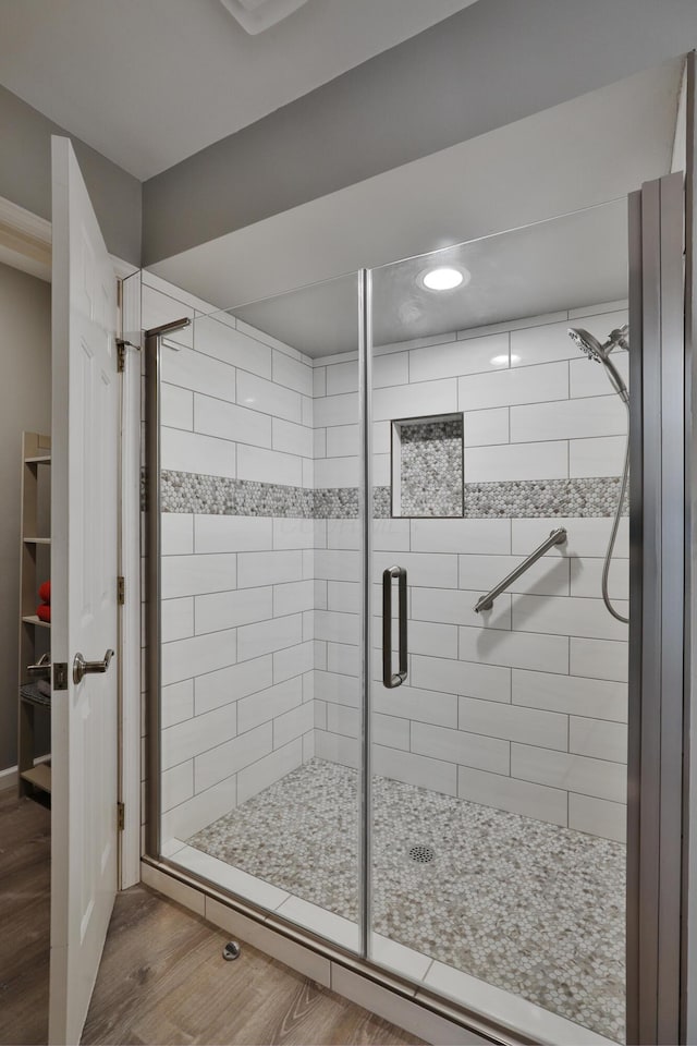 bathroom with wood-type flooring and a shower with door