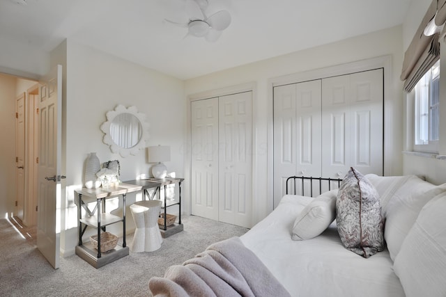 carpeted bedroom with two closets and ceiling fan