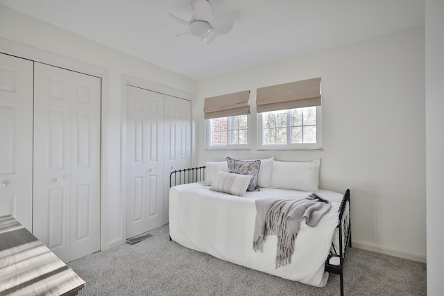 carpeted bedroom featuring multiple closets and ceiling fan