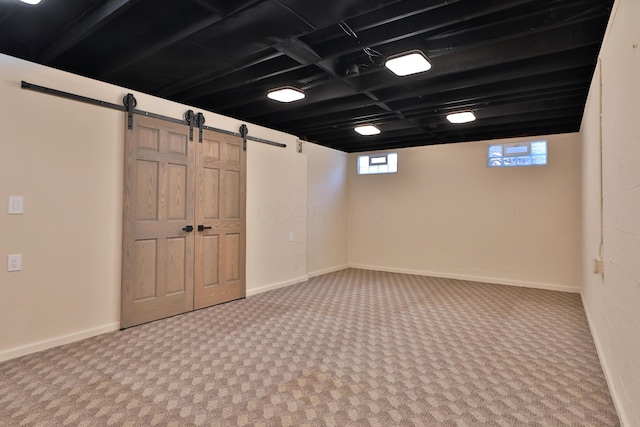 basement featuring a barn door and carpet flooring