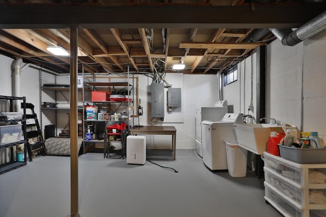 basement with sink, washing machine and clothes dryer, and electric panel