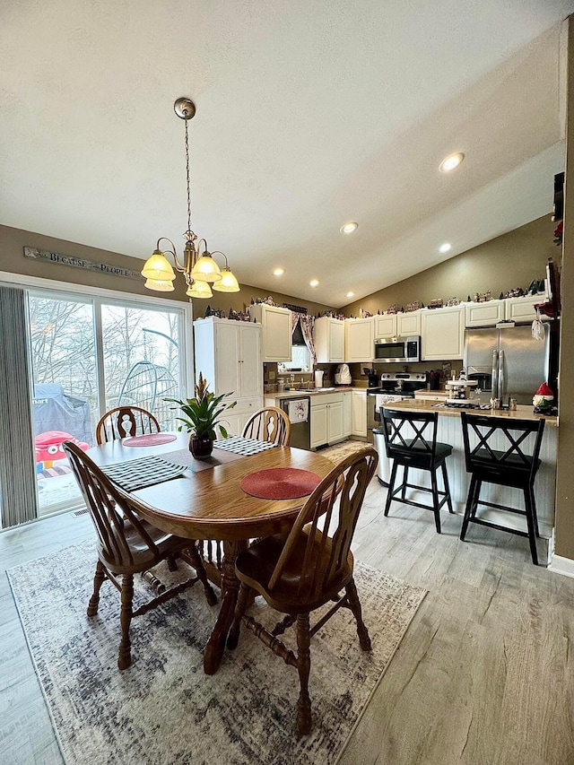 dining room featuring vaulted ceiling, a chandelier, a textured ceiling, and light wood-type flooring