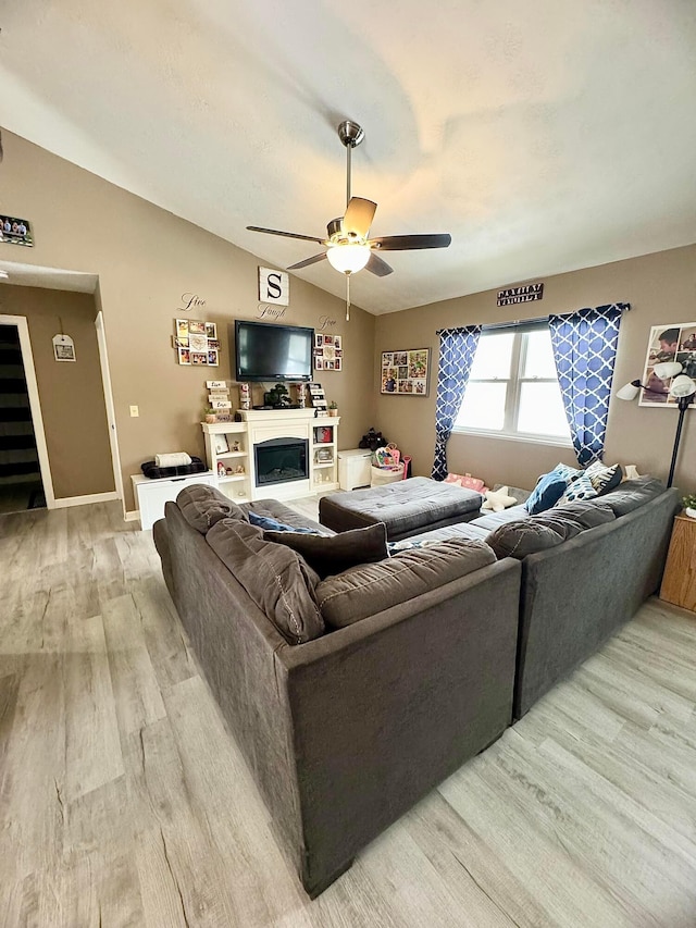 living room with light hardwood / wood-style floors, ceiling fan, and vaulted ceiling