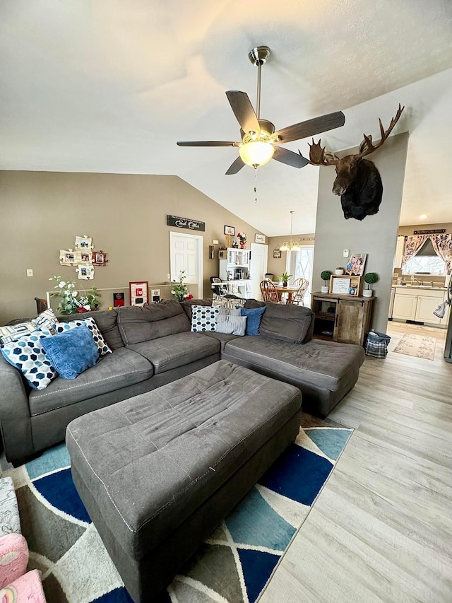 living room with ceiling fan, hardwood / wood-style floors, and vaulted ceiling