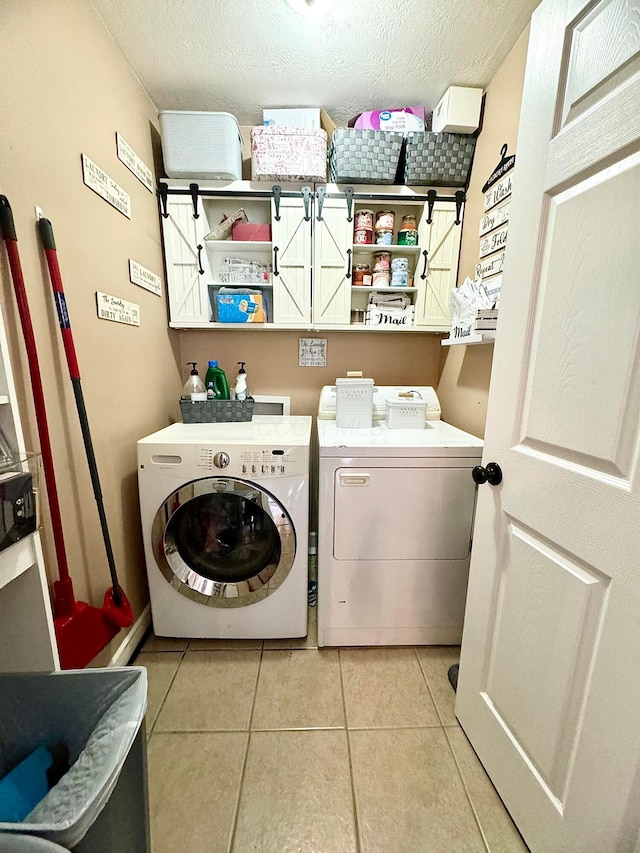 washroom with washer and clothes dryer, light tile patterned flooring, and a textured ceiling