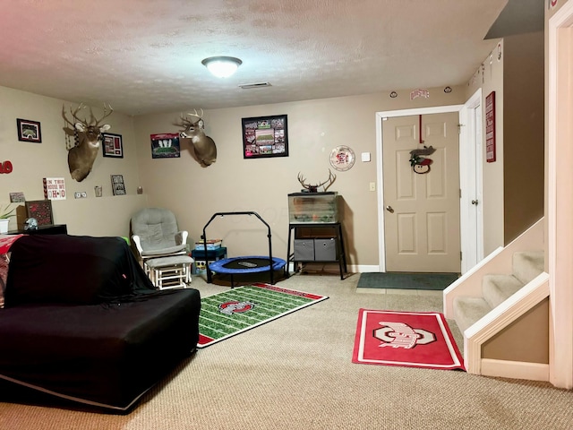 recreation room with a textured ceiling and carpet flooring