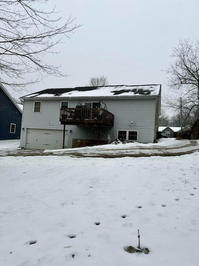 snow covered property featuring a garage and a deck