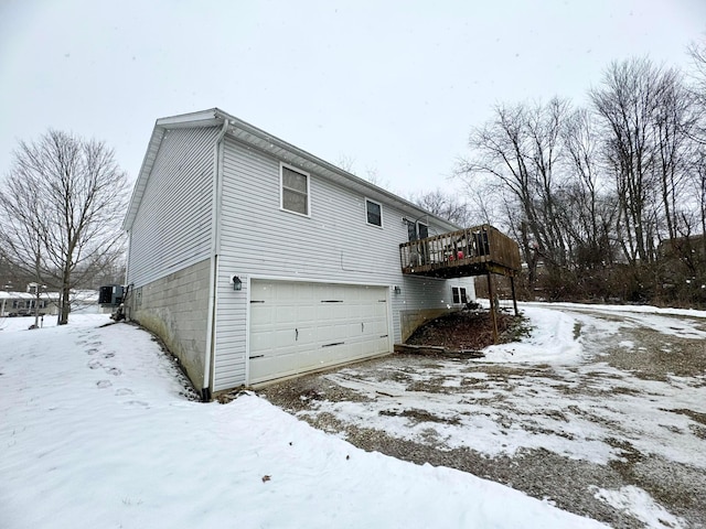 view of snowy exterior featuring a deck and a garage