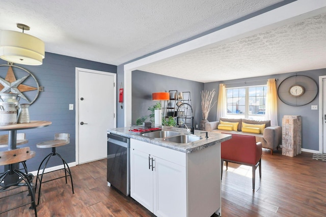 kitchen with white cabinets, a textured ceiling, dishwasher, and an island with sink