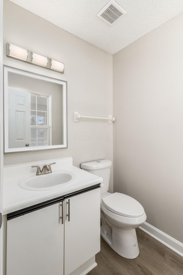 bathroom featuring toilet, vanity, a textured ceiling, and hardwood / wood-style flooring