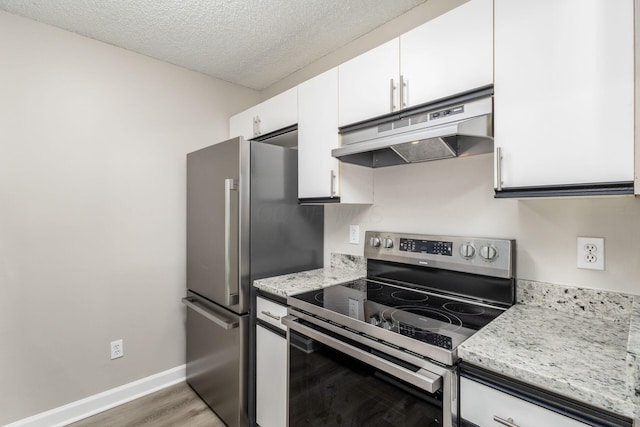 kitchen featuring light stone countertops, a textured ceiling, appliances with stainless steel finishes, white cabinetry, and hardwood / wood-style flooring