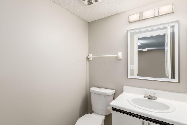 bathroom with a textured ceiling, toilet, and vanity