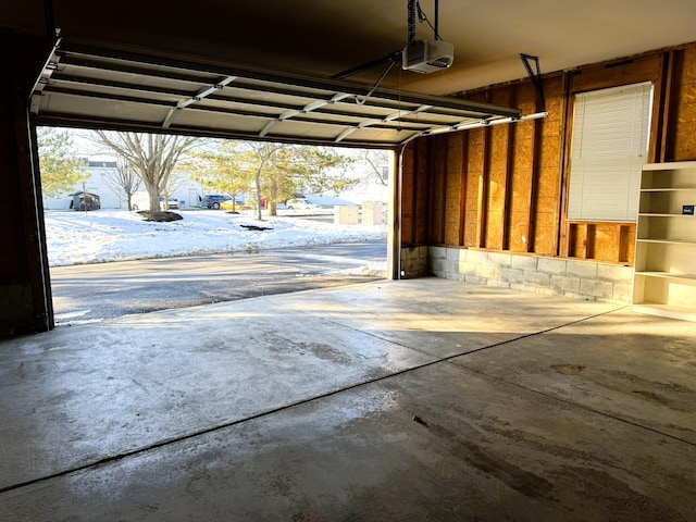 snow covered garage with a garage door opener