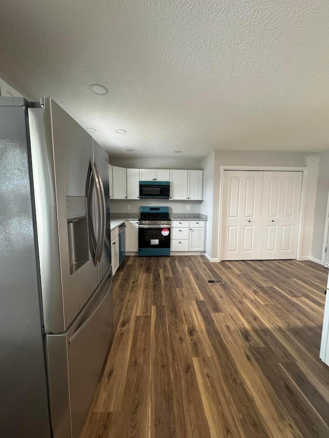 kitchen featuring a textured ceiling, dark hardwood / wood-style floors, white cabinets, and appliances with stainless steel finishes