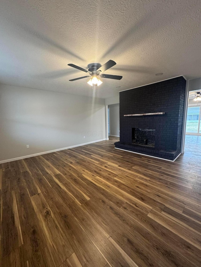 unfurnished living room with ceiling fan, dark hardwood / wood-style floors, a textured ceiling, and a fireplace