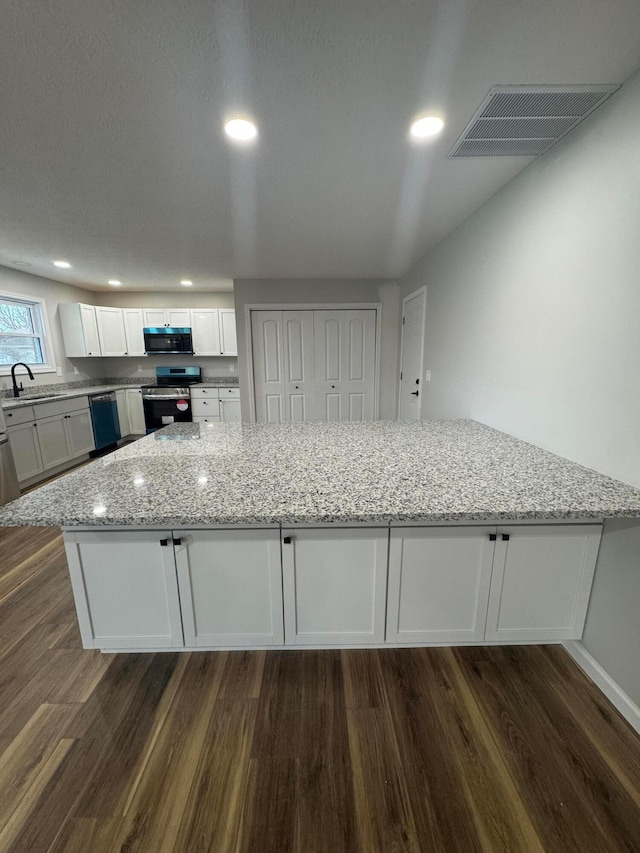 kitchen featuring stainless steel appliances, dark hardwood / wood-style floors, light stone countertops, and white cabinets