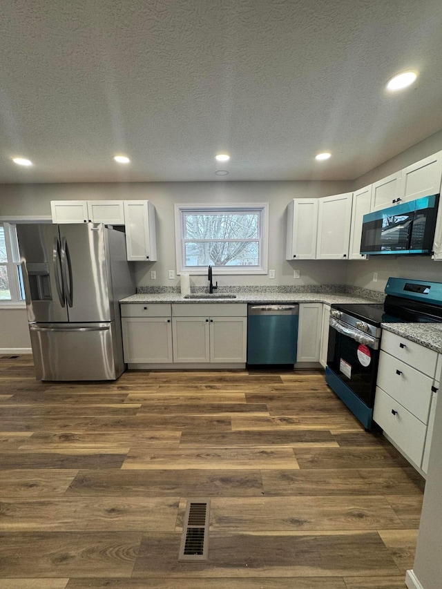 kitchen featuring appliances with stainless steel finishes, dark hardwood / wood-style floors, sink, and white cabinets