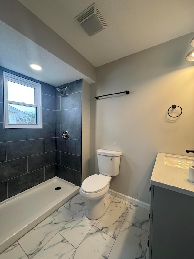 bathroom with vanity, toilet, and tiled shower