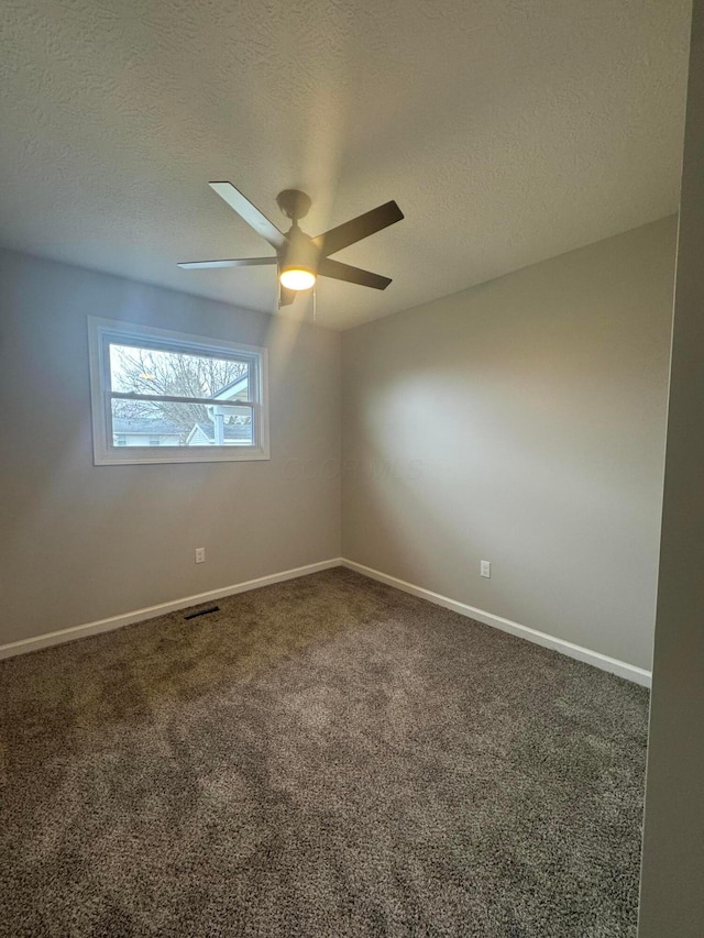 empty room with ceiling fan, dark carpet, and a textured ceiling