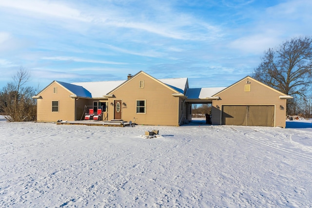 snow covered back of property with a garage