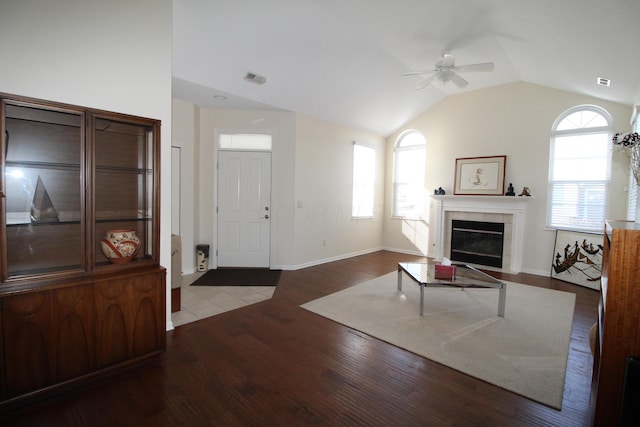 living room with a tiled fireplace, ceiling fan, a wealth of natural light, and hardwood / wood-style flooring