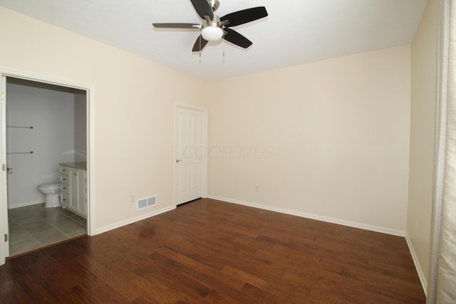 unfurnished bedroom featuring ceiling fan, ensuite bathroom, and dark hardwood / wood-style flooring