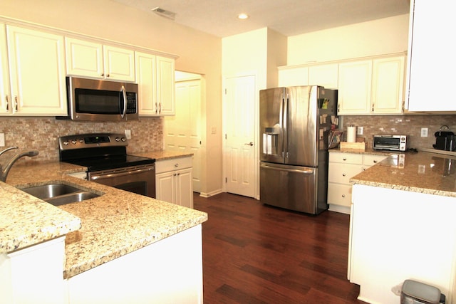 kitchen featuring sink, backsplash, light stone counters, white cabinetry, and stainless steel appliances