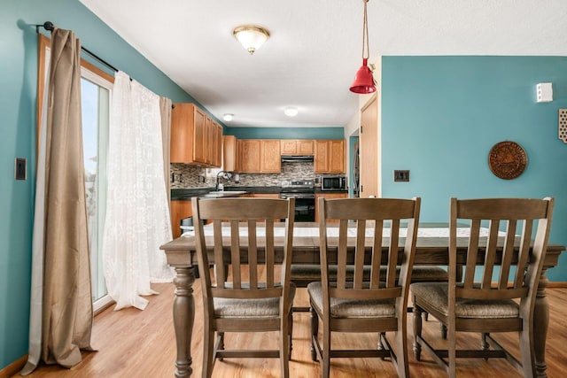 kitchen with stainless steel electric stove, sink, light hardwood / wood-style floors, and decorative backsplash